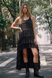 Vestido largo de fit fluido, sin mangas, escote redondo, detalle de capas de olanes y bajo asimétrico frontal.