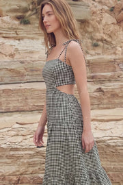 Vestido largo de corte en a, estampado cuadros, tirantes delgados con nudo amarrable, bajo con capas de olanes, cut out en costados y espalda. Detalle de rib elástico en cintura y fruncido en espalda.