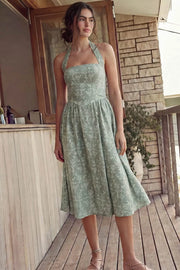Vestido midi de bordado floral, cuello halter con rib elástico, sin mangas, escote recto, cortes frontales, detalle frontal v en cintura con plisados y fruncido en espalda.