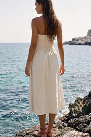 Vestido midi de lino, cuello halter con rib elástico, sin mangas, escote recto, cortes frontales, detalle frontal v en cintura con plisados y fruncido en espalda.