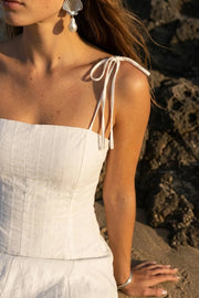 Vestido midi de rayas, corte en a, tirantes delgados con nudo amarrables, escote recto, cortes frontales y cierre posterior con cremallera oculta.