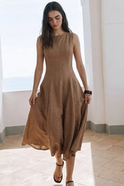 Vestido midi de lino, sin mangas, corte en a, cuello barco, escote en espalda y cortes frontales decorativos. Cierre lateral con cremallera oculta.